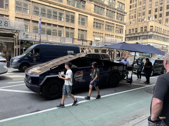 People lined up to receive pizza from a Tesla Cybertruck, on a New York street