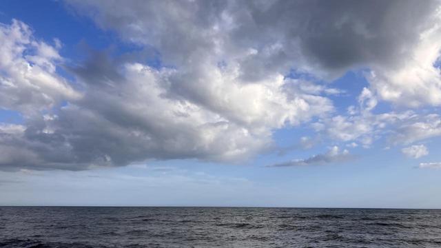 Grey ocean under a blue sky and grey clouds