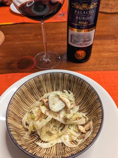 Fennel salad in a bowl with a bottle of Palacio de Burgo rioja wine and wine glass.