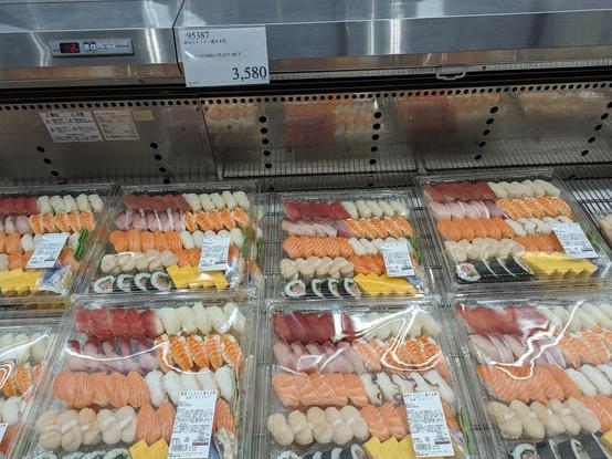 Square trays of nigiri sushi in an open top refrigerator. The price label above says 3580¥