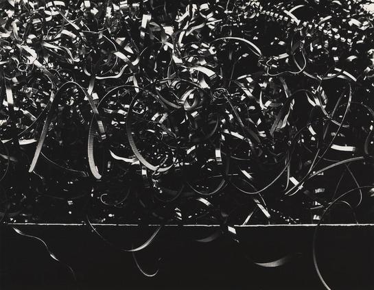 Black and white photo of a jumble of curled metal strips piled high