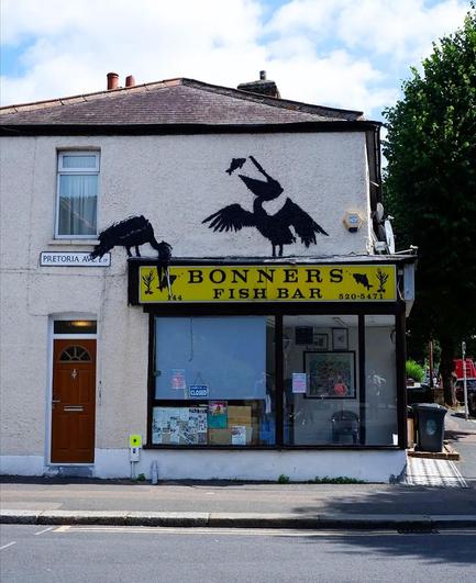 Streetartwall. A new Banksy featuring two black herons has appeared on the façade of a single-storey building with a fish takeaway. The two large birds were sprayed around the yellow store sign 