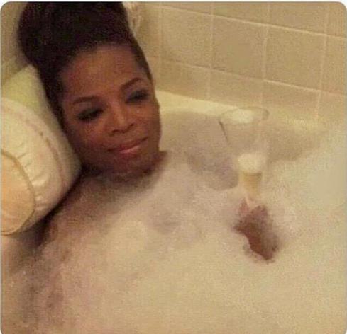 Oprah in a bathtub with a glass of bubbly