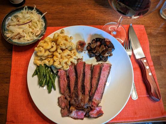 Plate with slices of ½ a ribeye steak fanned out a bit with other sides around