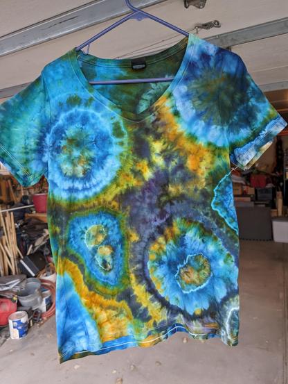 Tie dyed tee shirt in blues, purple with green and orange, done in 