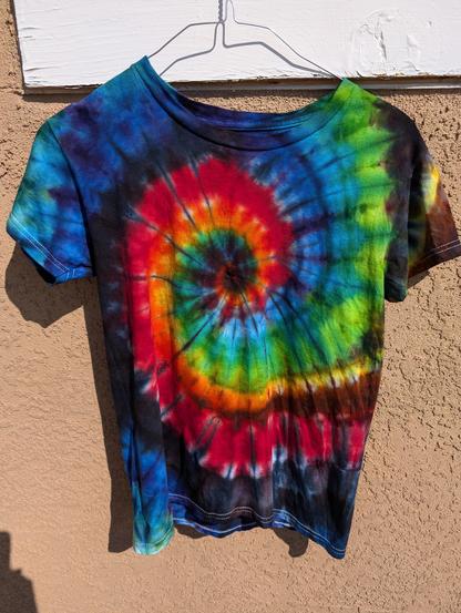 Rainbow-ish spiral tie dye tee shirt, orangey-red followed by green then blue and purple in a swirl from the center of the shirt. Ice-dyed, mostly.