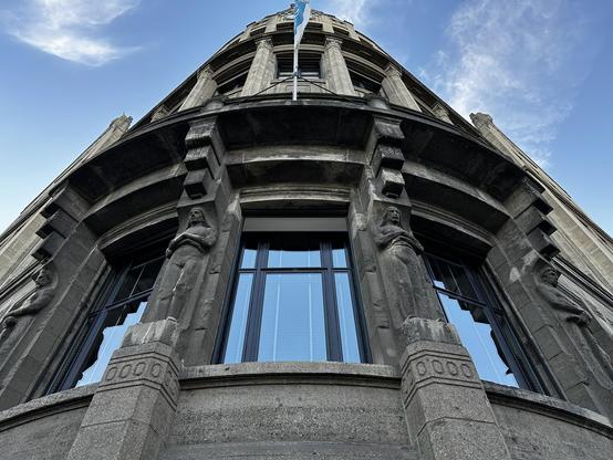 Lookup upwards to the Westerkadehuys building in Rotterdam, revealing figures in the supporting columns.