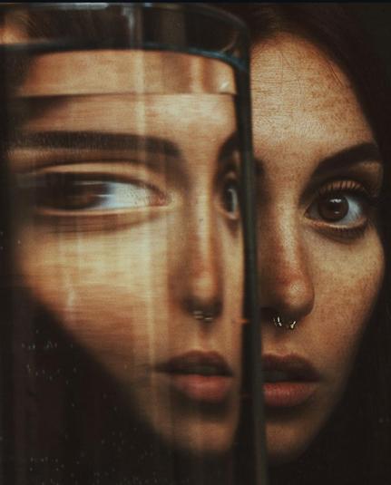 Photography. A color photo of a young woman next to a glass of water. The photo is kept dark, the focus is on half of the face of the beautiful dark-haired woman with brown eyes and a small nose ring. She is sharing the picture with a glass of water at the same height, which enlarges her face slightly, continues and distorts her right eye slightly, as if she were in motion. The fact that this gives her a small third eye in the center of the photo only makes it more interesting. A wonderful kind of portrait photography, perfectly staged.
Info: Alessio Albi is an Italian professional photographer who specializes in portrait, fine art and commercial/fashion photography.  Instead of taking an ordinary portrait, the photographer uses the peculiarities and characteristics of each unique environment to give the image an interesting aesthetic. He always takes his photos unprepared and then plays with shapes, colors, light and the special features that make each model unique.