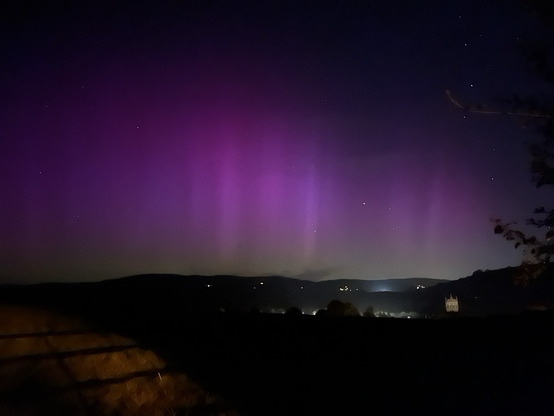 Night sky scene landscape view foreground dark. Numerous vertical pillars of purple light with a green hue underneath