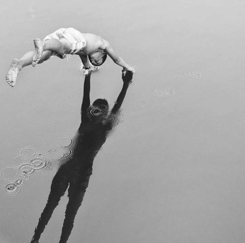 person doing handstand on wet sand with shadow mirroring their body — photographer unknown