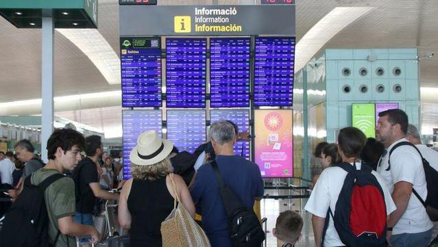 Persones mirant una pantalla de l'aeroport del Prat (ACN/Albert Hernàndez)