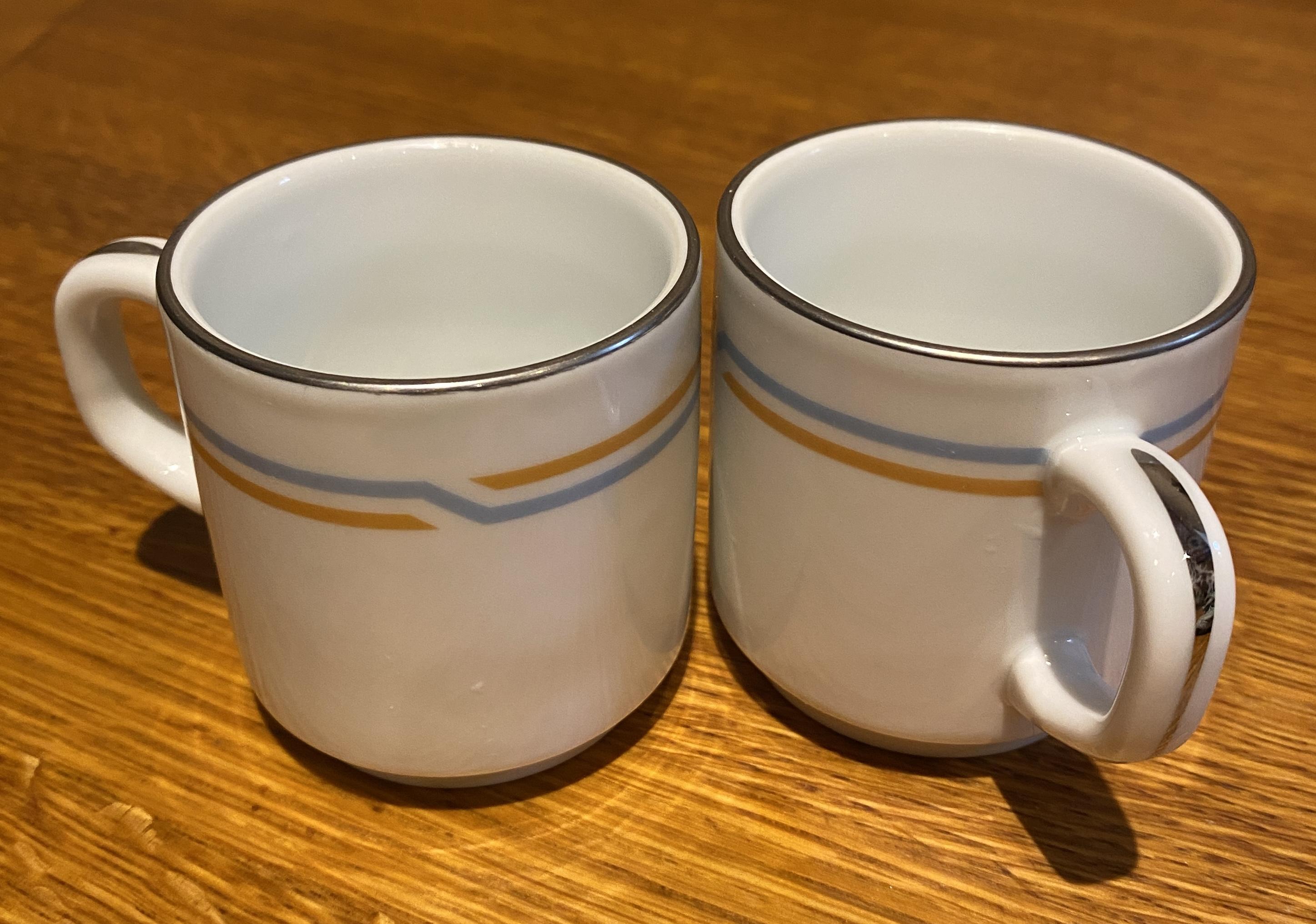 The cups. White, stackable. And double orange and blue stripe circumvents the base. There some really shiny silvery details on the handle and top.