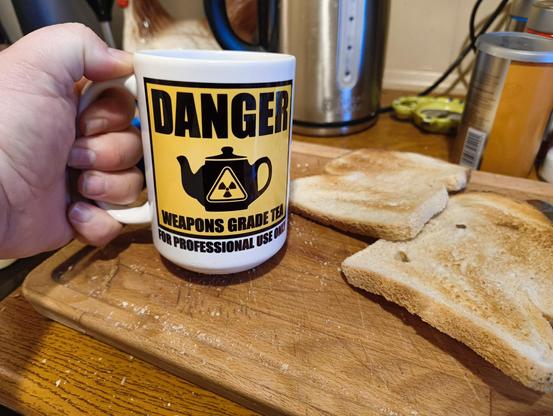 Two slices of toast on a wooden cutting board and a 15oz mug with an industrial sign styled message 