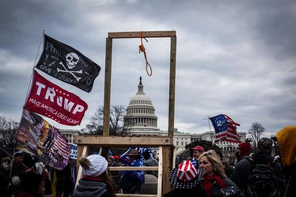 Gallows and Trump flags framing the capitol building on Jan 6