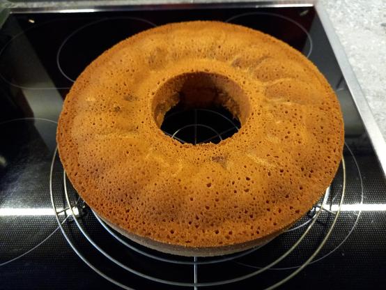 Ein frisch gebackener runder Marmorkuchen, der auf einem runden Kuchengitter zum Auskühlen auf einem Cerankochfeld steht