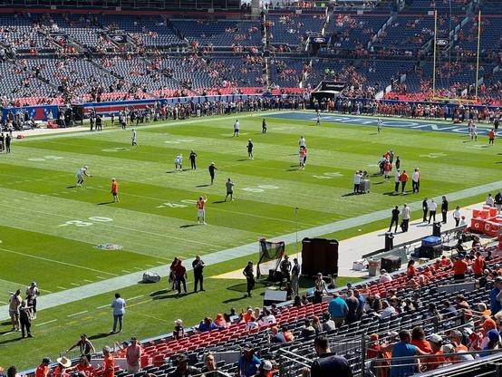 A football field in a stadium with several players warming up.