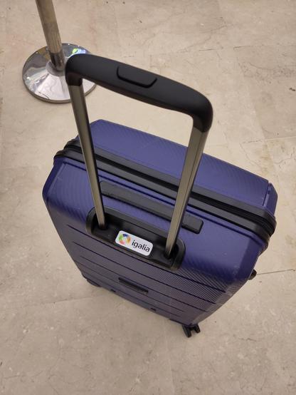 Picture of a blue suitcase with an Igalia sticker near the handle