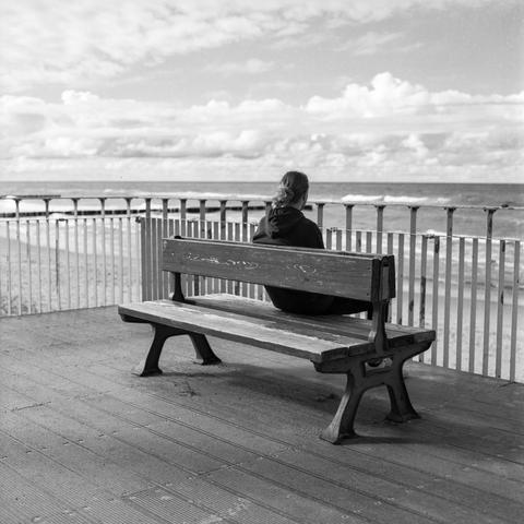 Black and white photo showing a seated wanderer gazing out to sea.