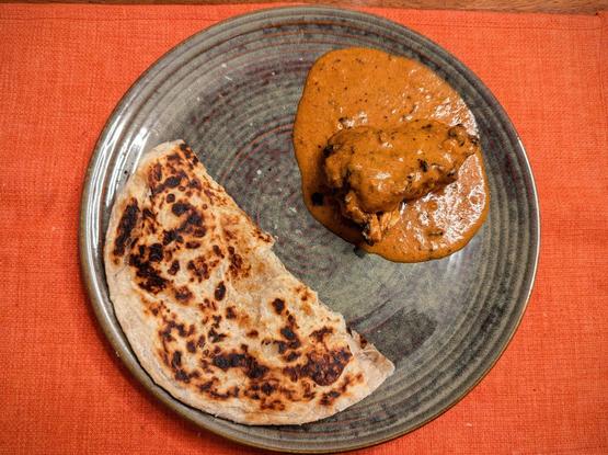 Butter Chicken and a folded paratha on a plate