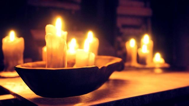 A table with a bowl holding a set of candles, with more candles blurred in background.