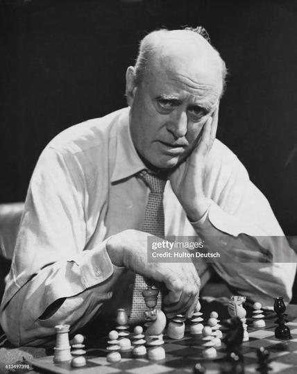 In a publicity photo for the BBC's 1950 production of Mr. Gillie, Alastair Sim sits at a chess board wearing a tie and a forlorn look.