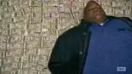 A man laying on a giant pile of money, his eyes closed, resting comfortably.