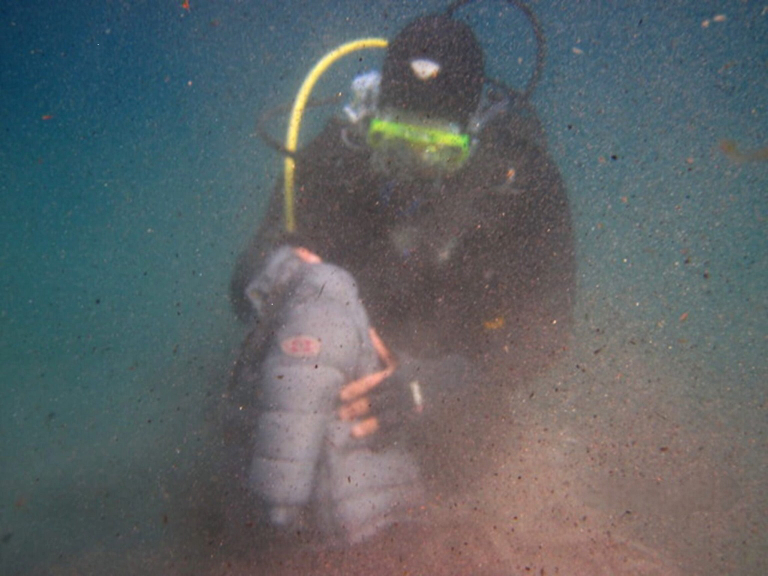 Unterwasseraufnahme eines Tauchers im Mittelmeer, der eine Kinderjacke in den Händen hält. 