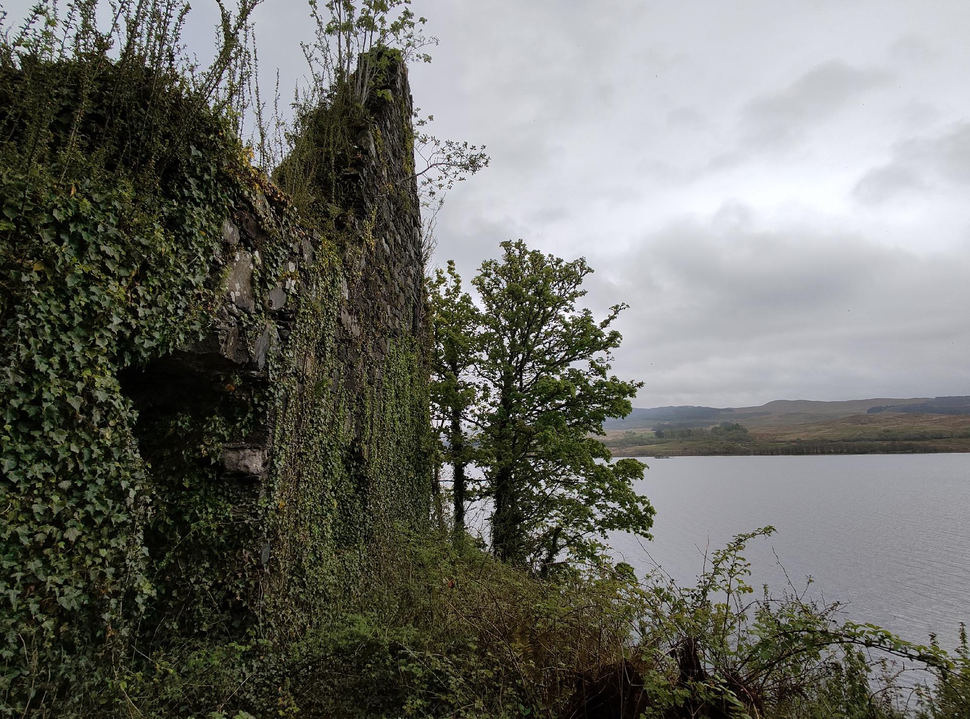 Ruined castle wall on an island with view out to loch behind.