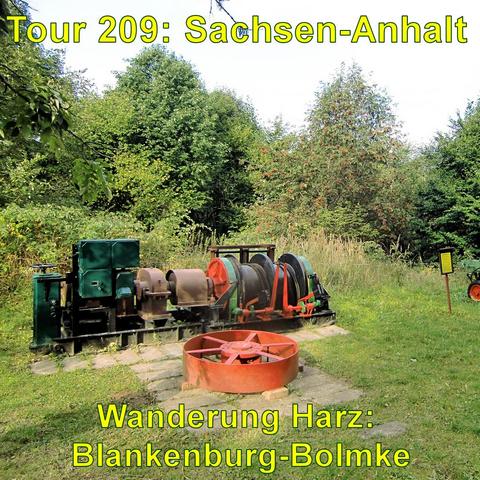 Alte Bergbaumaschinen und -geräte im Freien im Schaubergwerk Büchenberg, darunter Winden mit Seiltrommeln, umgeben von Grünanlagen.