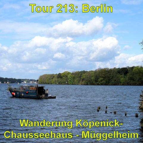 Ein kleines Schiff liegt auf einem See mit blauem Wasser. Im Hintergrund befindet sich ein bewaldetes Ufer und über dem Ganzen ein Himmel mit einigen großen, weißen Wolken.
