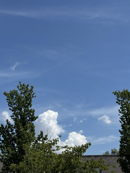 Blue sky with a few clouds and a faint contrail. 