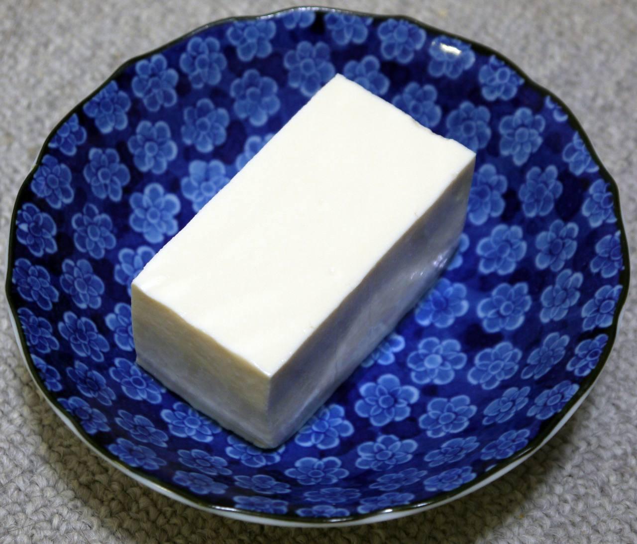 Das Foto zeigt einen blauen Teller mit einem Stück Tofu darauf