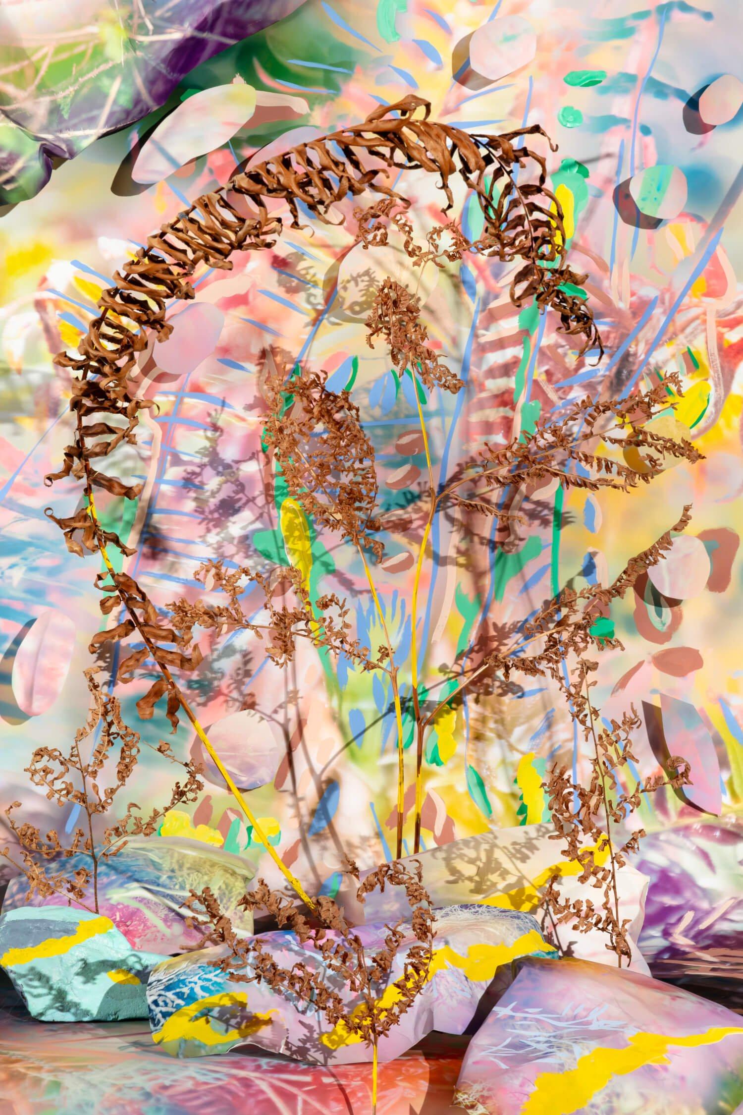 Mixed media tableau in soft colors with dry brown leaves placed within painted rocks and paper cut outs.