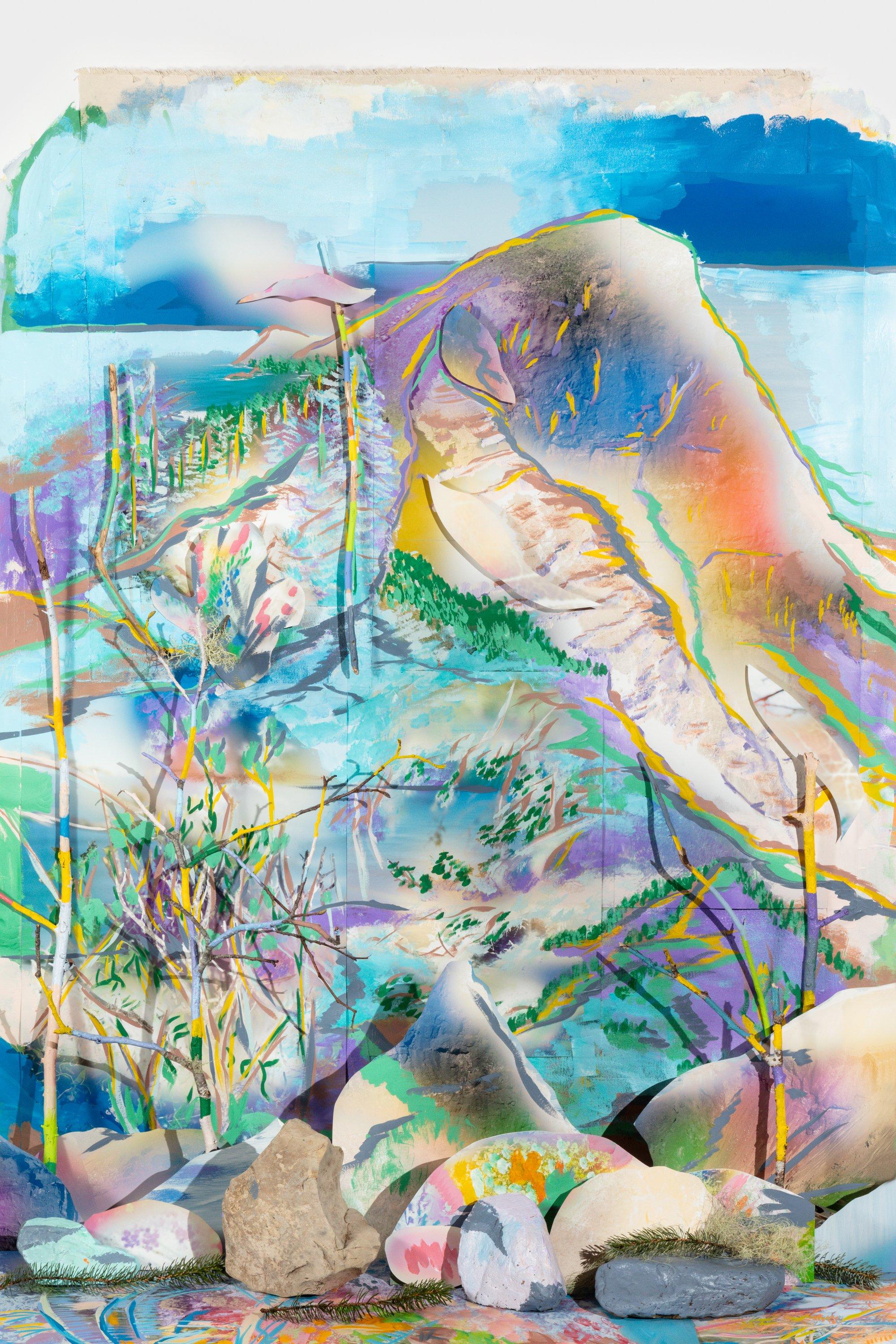 Mixed media tableau with painted twigs and rocks set within a painted mountain background with paper cutouts in bright colors.