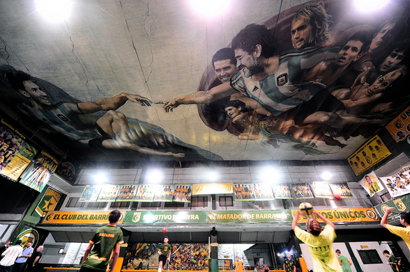 Photograph of "The Sistine Chapel of Football" (also known as "The Creation of Football") is an artwork exhibited at the Sportivo Pereyra club from Barracas in Buenos Aires, Argentina. It honors two Argentine footballers, Lionel Messi and Diego Maradona, as well as other notable Argentine players including Juan Román Riquelme, Gabriel Batistuta, Mario Kempes, Sergio Agüero, Claudio Caniggia, Ricardo Bochini and Ariel Ortega. Source: Wikipedia.