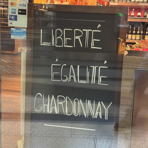 Photo of a sign in front of a wine shop in Zurich, Switzerland, reading "Liberté, Égalité, Chardonnay"