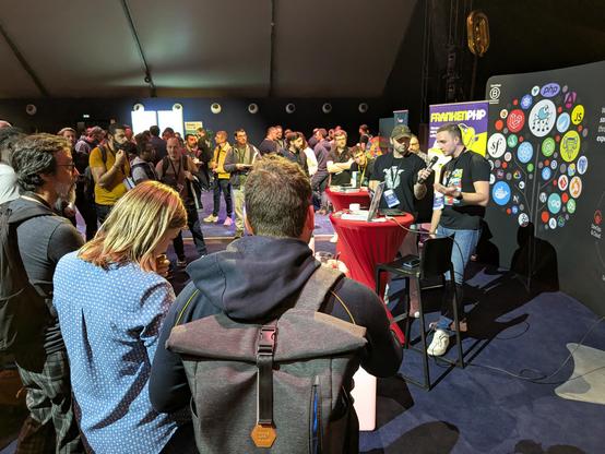 a crowd attending a talk from two people on a booth at an event