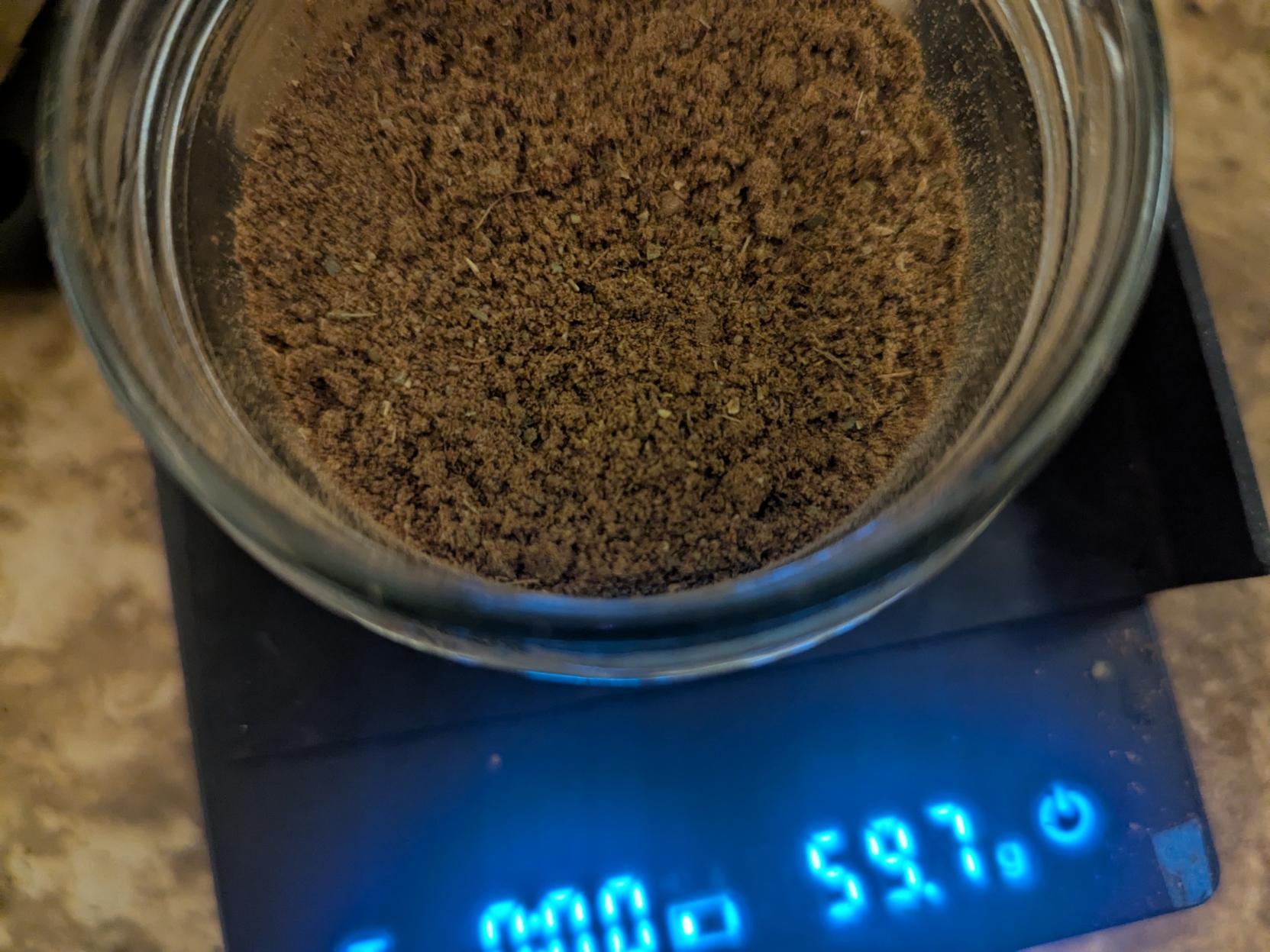 59.7 g illuminated on a small digital scale and a small glass jar with brown powder