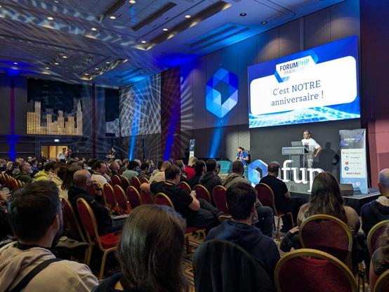 There is a man giving a speech in front of a seated audience