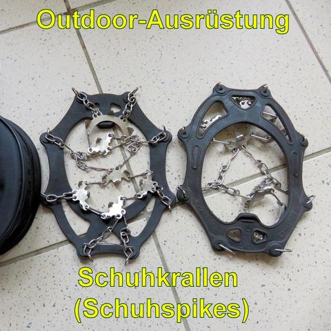 Ein Paar Schuhkrallen (Schuhspikes) liegt auf einem gefliesten Boden. Die Krallen bestehen aus robustem Gummi, das über den Schuh gespannt wird, und Metallketten mit spitzen Zacken, die für besseren Halt auf Eis oder Schnee sorgen. Die Metallspikes sind an den Ketten befestigt, um zusätzliche Traktion zu bieten. Daneben liegt eine schwarze, runde Transporttasche mit Reißverschluss. Die Schuhkrallen sind ideal für winterliche Outdoor-Aktivitäten oder rutschige Untergründe.