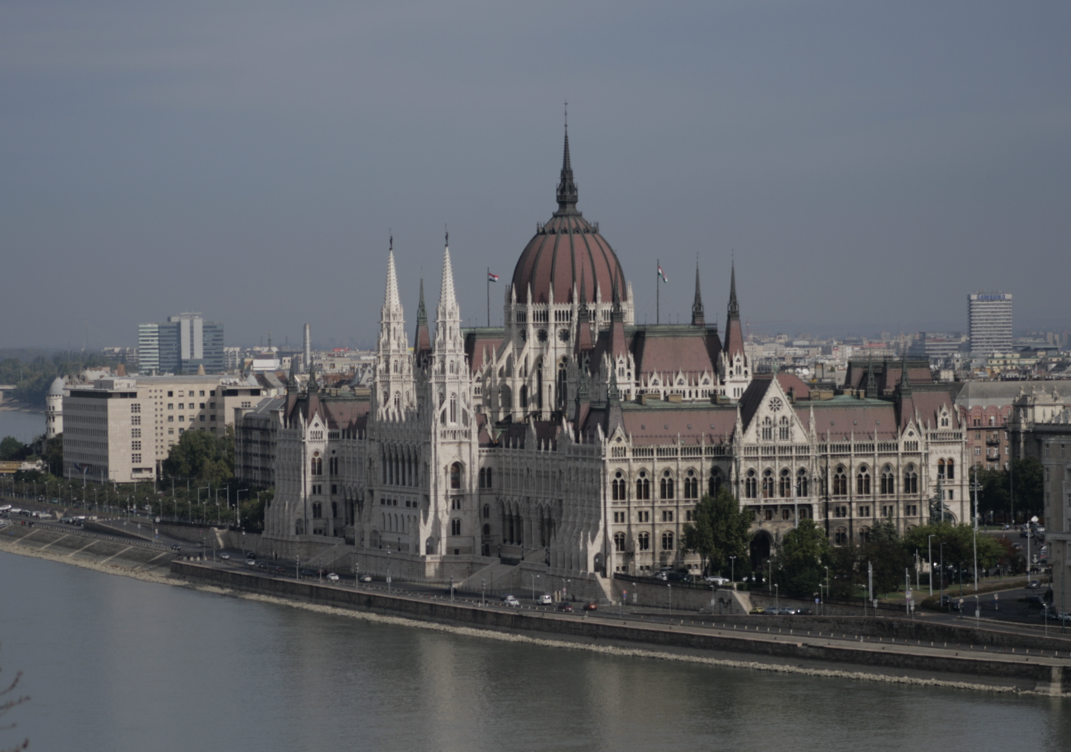 majestic domes and spires rise from grand architecture on the banks of a river in this photo of part of Budapest