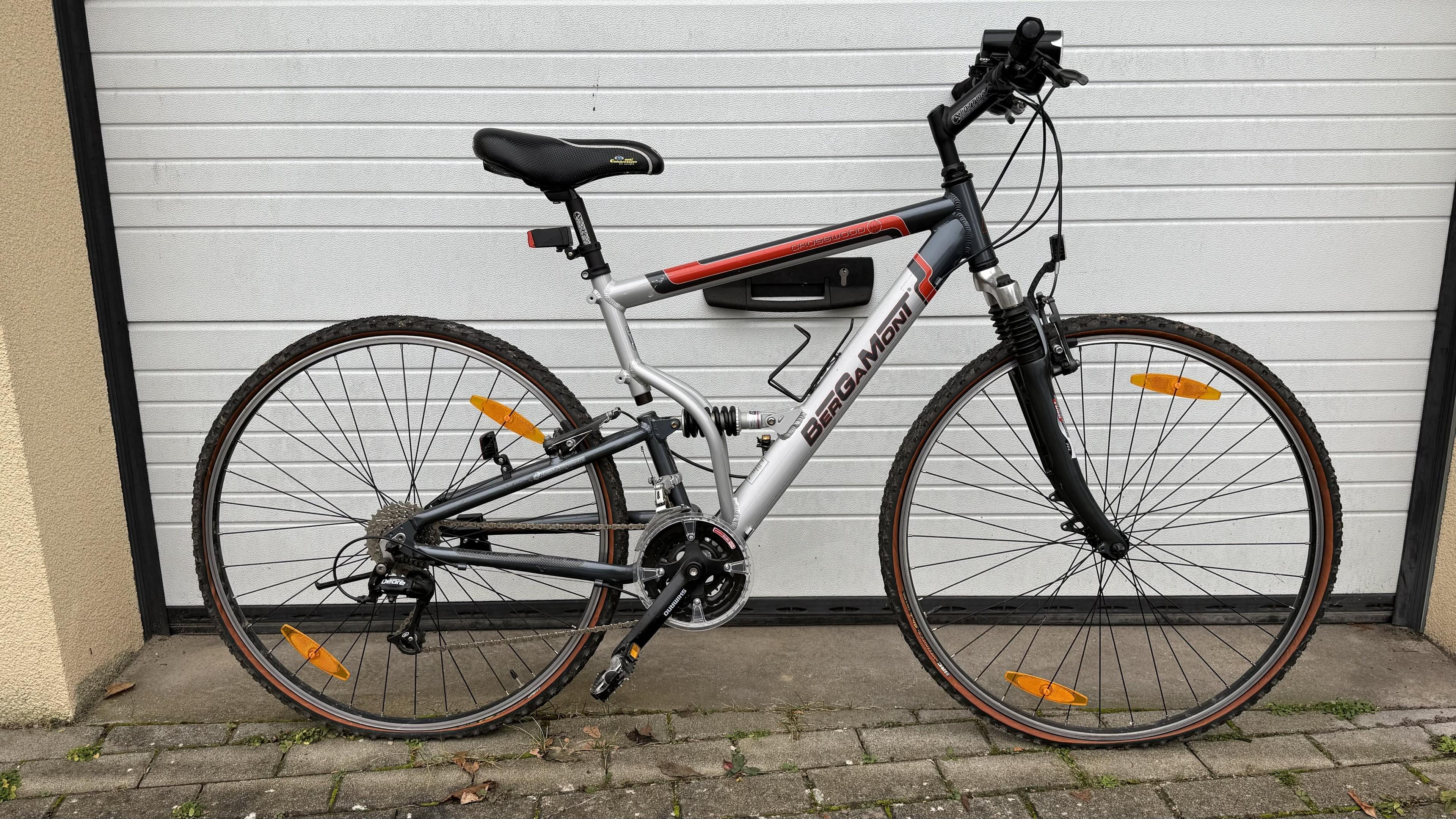 Ein mountainbike mit schwarzem, silbernem und rotem Rahmen, vor einer weißen Rolltor.