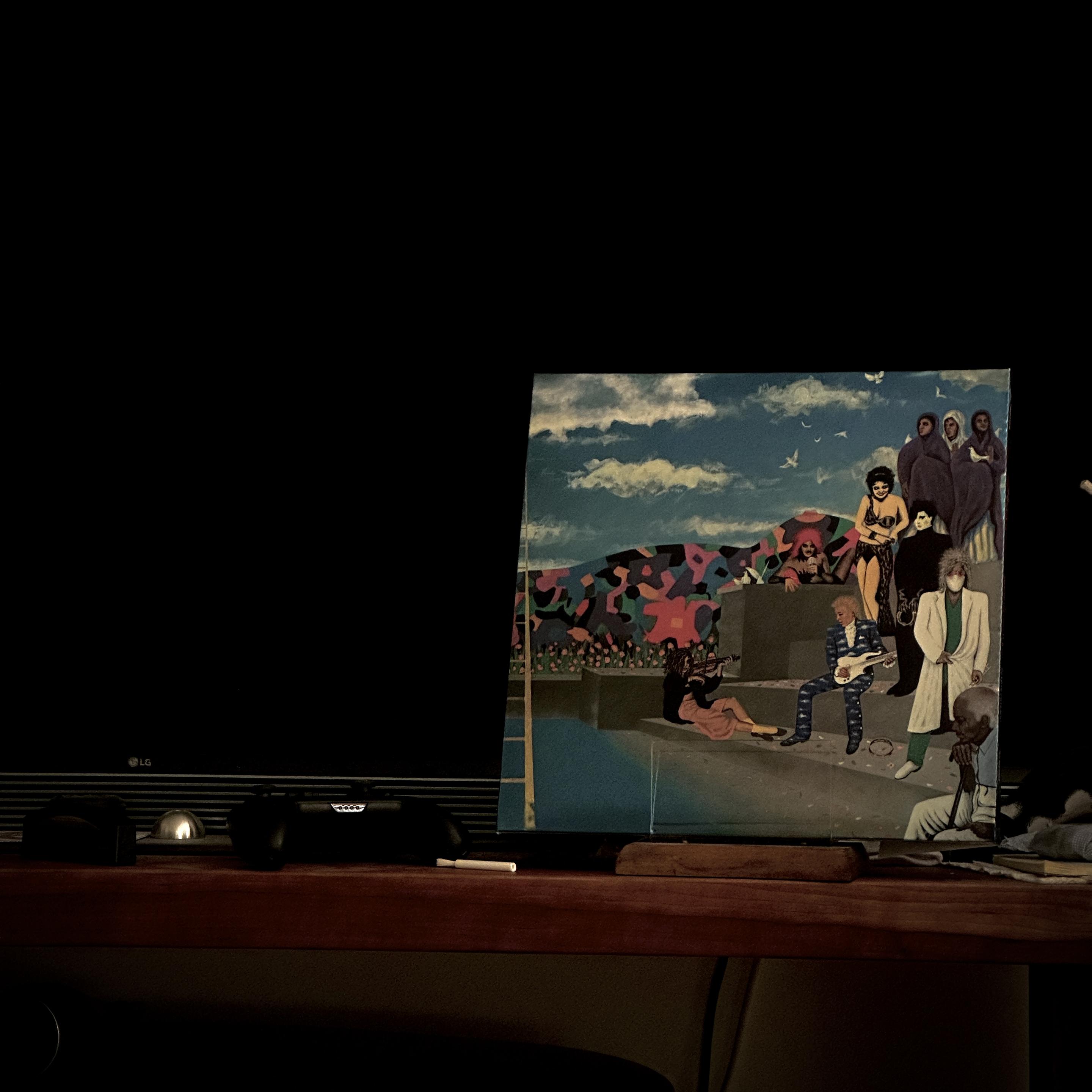 My Now Playing prop with Prince’s Around the World in a Day album. It’s a fairly faithful reproduction of the original vinyl version, but it’s using metallic inks. It shows a complex ‘outsider art’ mural of various characters depicted in the album and members of the Revolution. There is no text on the cover (the balloon boy title is on a sticker which was affixed to the shrinkwrap like the OG pressing)