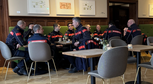 Een tiental brandweerlieden aan de koffie