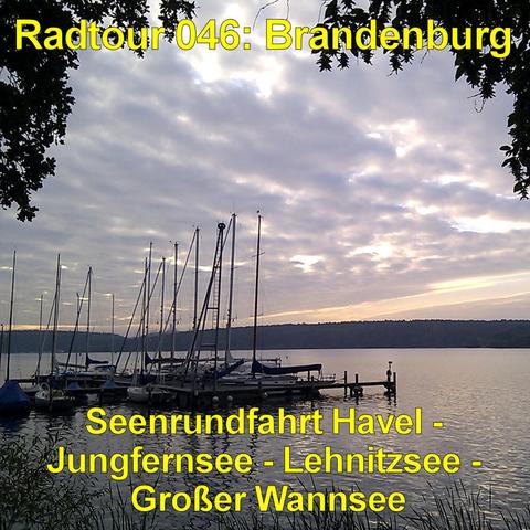 Mehrere Segelboote liegen ruhig an einem Steg auf einem See. Ihre hohen, schlanken Masten ragen dicht nebeneinander in den Himmel. Das Wasser ist glatt und spiegelt die sanften Farben des Abendhimmels wider. Am Horizont zieht sich ein dunkler Uferstreifen mit flachen Hügeln entlang. Der Himmel zeigt weiche Wolken in Rosa-, Blau- und Grautönen, durch die das letzte Licht scheint. Dunkle Blätter und Äste rahmen das Bild oben wie ein natürlicher Bogen ein. Die Stimmung wirkt still und friedlich.