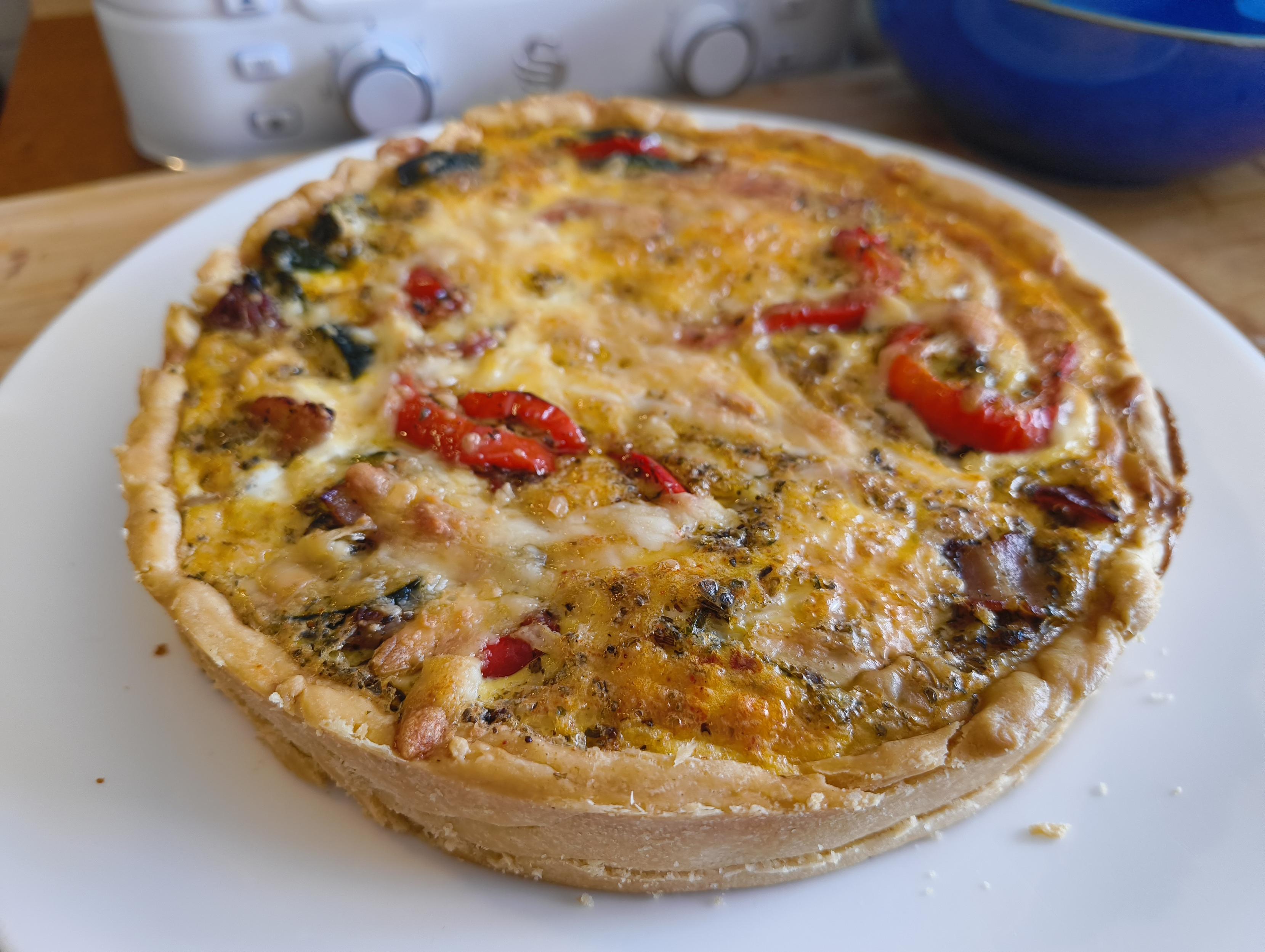 A freshly made quiche cooling on a plate.