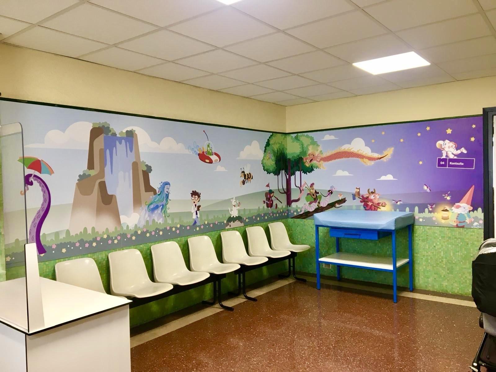 A colorful children's waiting room featuring a whimsical mural with a waterfall, fantasy characters, and animals. There are white plastic chairs facing the mural, and a blue diaper change table against the wall.