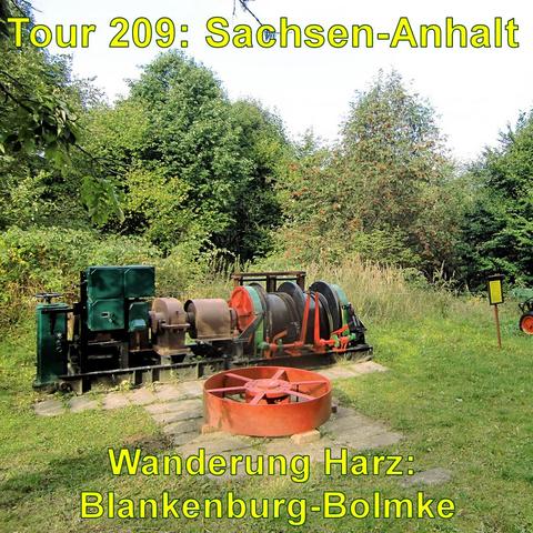 Alte Bergbaumaschinen und -geräte im Freien im Schaubergwerk Büchenberg, darunter Winden mit Seiltrommeln, umgeben von Grünanlagen.