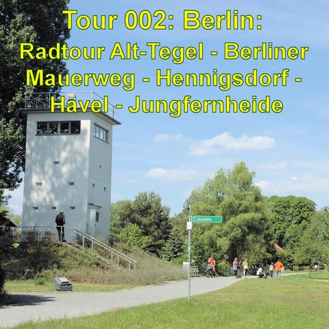 Ein ehemaliger Wachturm, umgeben von grünen Bäumen, steht im Mittelpunkt eines weitläufigen Parks. Ein paar Menschen spazieren und radeln auf einem asphaltierten Weg entlang, der sich durch die grüne Landschaft schlängelt. Der Wachturm hat eine helle, weiße Fassade und Treppen, die zu seiner Plattform führen. Ein Wegweiser mit der Aufschrift Gaststätte steht rechts im Bild. Der Himmel ist blau mit wenigen Wolken, und die Szenerie wirkt ruhig und einladend, ideal für einen Ausflug oder eine Radt…