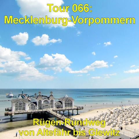 Seebrücke mit einem großen, hellen Gebäude auf Stelzen ragt vom Sandstrand ins Meer. Das Bauwerk besitzt mehrere Giebel, große Fensterfronten und Türmchenartige Dachaufbauten. Ein langer Steg führt vom Strand dorthin. Rechts erstreckt sich ein breiter Strand mit zahlreichen weißen Strandkörben in geordneten Reihen. Menschen sind vereinzelt am Wasser und auf dem Steg unterwegs. Das Meer zeigt ruhige, flache Wellen in türkisblauer Färbung. Der Himmel ist strahlend blau mit großen, weißen Wolken.
